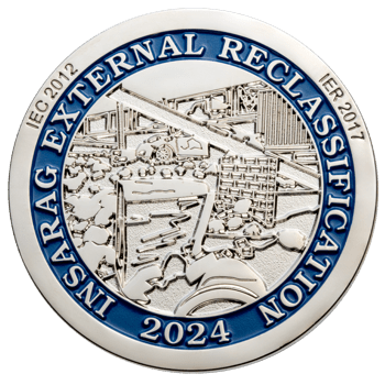 Silver challenge coin featuring blue enamel border with INSARAG External Reclassification 2024 text and detailed relief of rescue equipment.