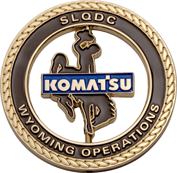 Gold-rimmed challenge coin featuring the Komatsu logo over a cowboy silhouette with SLQDC and Wyoming Operations text.