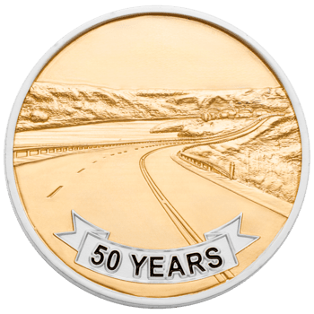 Gold and silver challenge coin featuring a 50 years banner and an embossed winding highway through a mountain landscape.