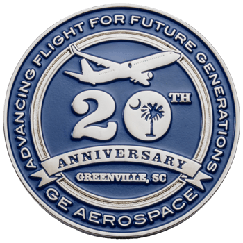 A silver and blue GE Aerospace 20th Anniversary coin featuring an airplane, a South Carolina palm and crescent moon logo, and Greenville, SC text.