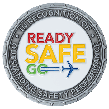 Silver challenge coin with 'Ready Safe Go' text in red, yellow, and green enamel, featuring an airplane icon and 'Outstanding Safety Performance' border.