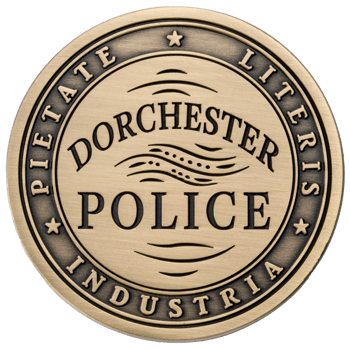 Round antiqued brass medallion for Dorchester Police featuring the Latin motto Pietate Literis Industria and wave-like patterns.