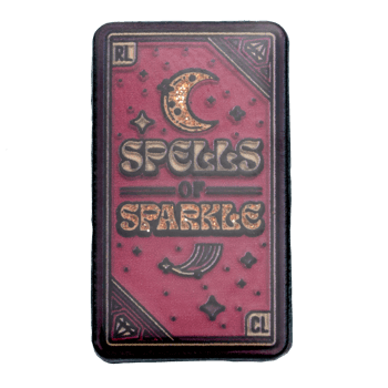 Rectangular Spells of Sparkle lapel pin with a pink glitter background, crescent moon, and celestial icons.